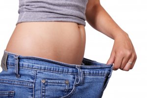 Fertilidade feminina e obesidede. Mulher magra, com calça jeans larga, segurada com a mão.