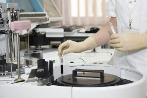 Mão com luva manipulando tubos de ensaio em laboratório em tratamentos para infertilidade.