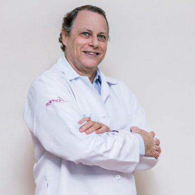 Dr. Philip Wolff, de jaleco e braços cruzados, especialista em inseminação artificial.