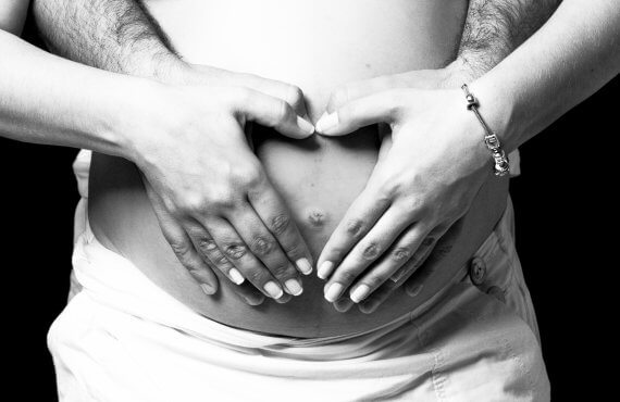 Maos de homem e mulher sobre o ventre da grávida após a FIV