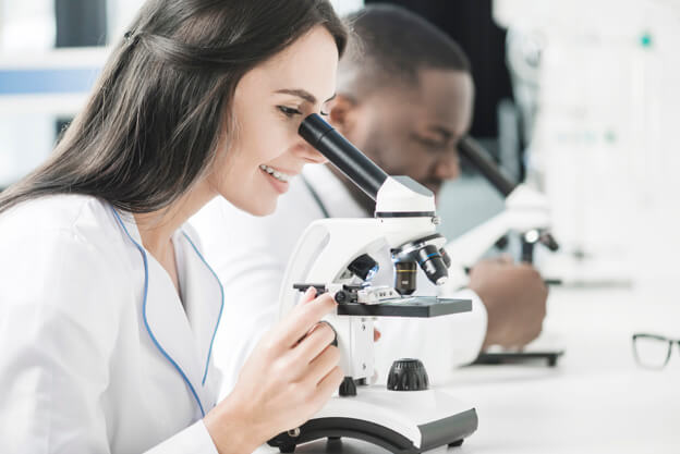 Mulher em laboratório de reprodução humana assistida olhando por microscópio