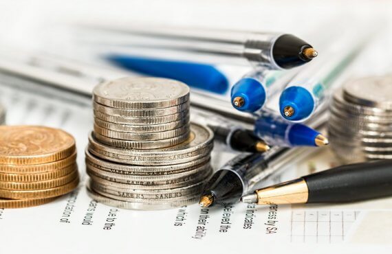 moedas, canetas e papel para calcular quanto custa a FIV