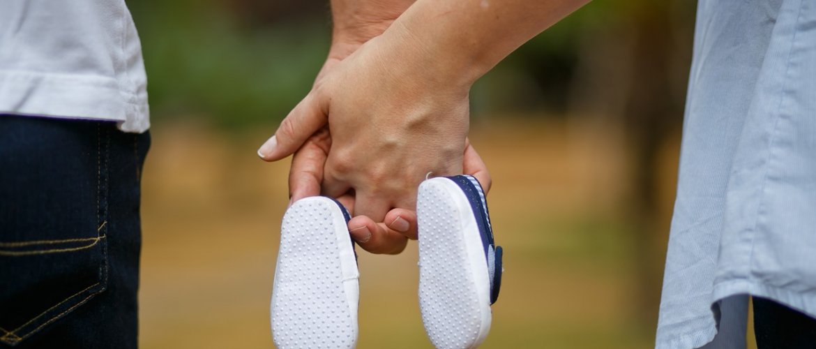 Casais soropositivos de mãos dadas segurando sapatinhos de bebê